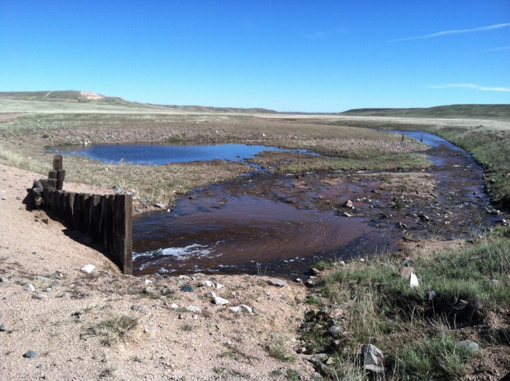 Photograph 10. This image captures a rare event with Lone Tree Creek flowing in the area north of the Intercept Transect, during runoff following heavy storms. The sandy, gravelly character of the coarser Ogallala alluvial fan sediments is observable in the stream and the roadway at left.