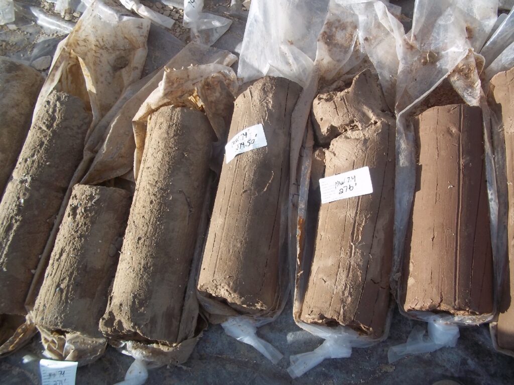 Photograph 4. Typical sonic cores of Brule silty claystone (five core pieces at left) and clay (rightmost core). These cores were retrieved from near the bottom of the Brule Member of the White River Formation at the MW74 location (in flame pit at LSB 1). The core depth shown here (270-277 ft bgs) is approximately 100 feet below the zone of contamination at this location; the Brule material encountered through this interval consists of layers of clay, hard claystone, clayey silt, silty claystone, siltstone, and silty clay.
