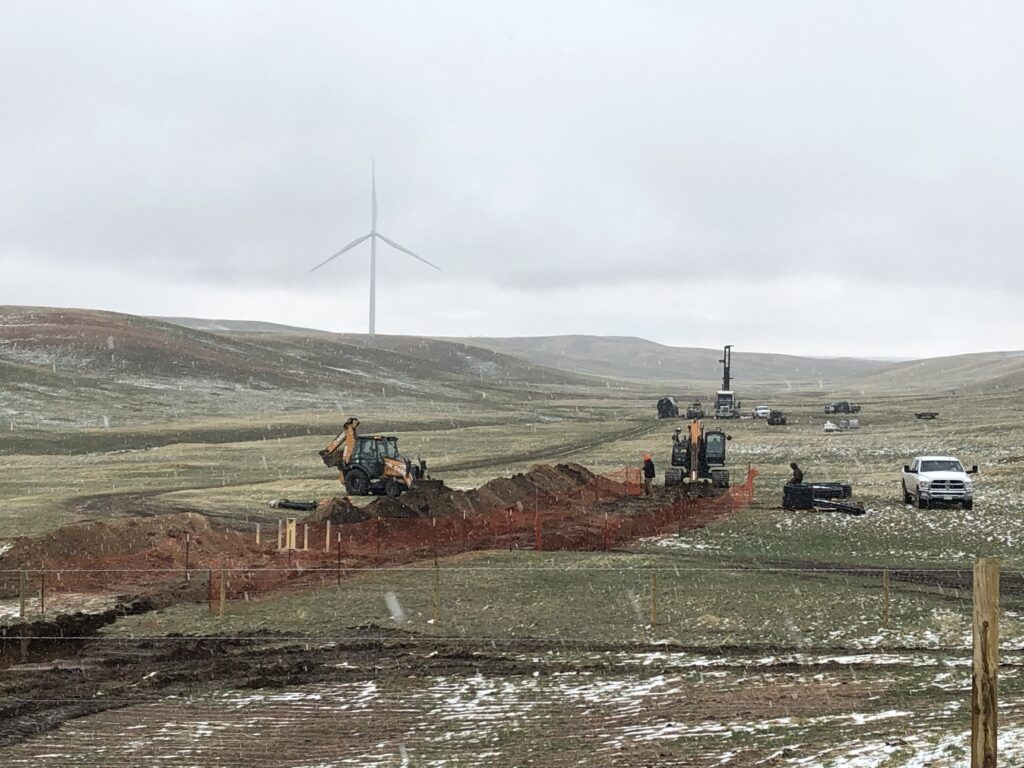 Photograph 12. Construction of the Pump, Treat, and Inject (PTI) pilot test at the Intercept Transect began in May 2021. The backhoe and excavator are at the approximate location of the PTI shed to be built to house the activated carbon adsorption tanks. The drill rig in the distance began drilling the injection well at this time, 700 feet east of the shed location.